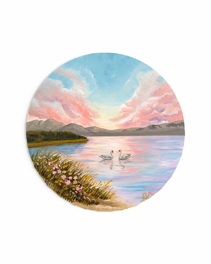 Two swans on a still lake at pastel sunset